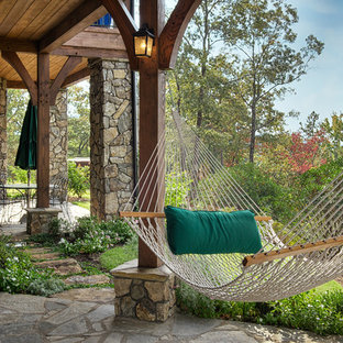 Esempio di un patio o portico stile rurale con pavimentazioni in pietra naturale e un tetto a sbalzo
