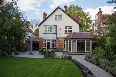 This is an example of a medium sized classic back patio in London with natural stone paving.