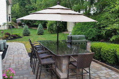 Modelo de patio clásico de tamaño medio en patio trasero con cocina exterior y adoquines de piedra natural