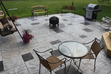 This is an example of a medium sized traditional back patio in Cincinnati with a fire feature, stamped concrete and no cover.