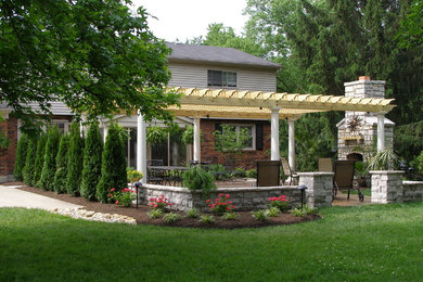 Inspiration pour une terrasse arrière traditionnelle avec un foyer extérieur et une pergola.