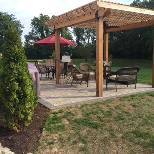 Immagine di un patio o portico stile americano di medie dimensioni e dietro casa con un focolare, pavimentazioni in mattoni e una pergola