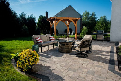 Photo of a medium sized classic back patio in Columbus with a fire feature, natural stone paving and a pergola.