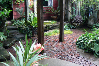 Foto de patio exótico pequeño en patio trasero con fuente, adoquines de ladrillo y pérgola