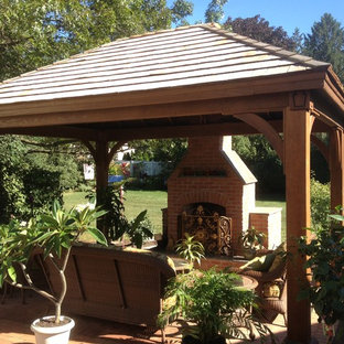 Foto di un patio o portico american style di medie dimensioni e dietro casa con un focolare, pavimentazioni in mattoni e un gazebo o capanno