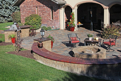 Example of a large classic backyard concrete paver patio kitchen design in Other with no cover