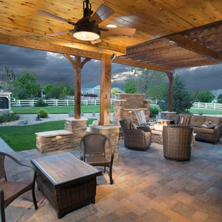 Ispirazione per un ampio patio o portico stile rurale dietro casa con un focolare, pavimentazioni in mattoni e una pergola