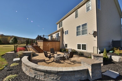 Example of a large minimalist backyard stamped concrete patio design in Philadelphia with a fire pit