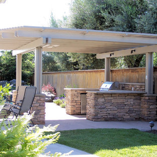 Aménagement d'une terrasse avec une cuisine extérieure arrière craftsman de taille moyenne avec une dalle de béton et une pergola.