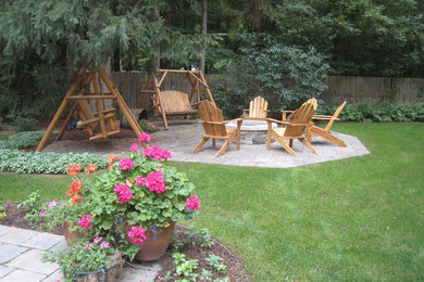 Example of a classic backyard stone patio design in Grand Rapids with a fire pit and no cover