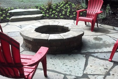 Diseño de patio sin cubierta en patio trasero con brasero y adoquines de piedra natural