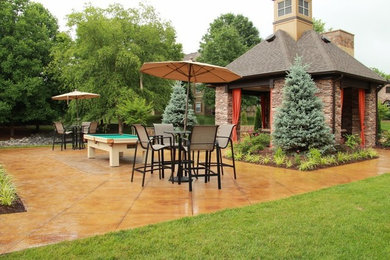 Modelo de patio de tamaño medio en patio trasero con cocina exterior, suelo de hormigón estampado y cenador