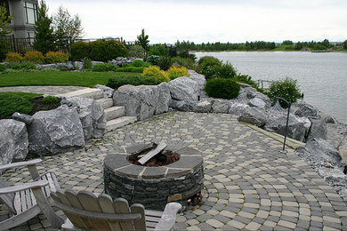 На фото: двор на заднем дворе с местом для костра и покрытием из каменной брусчатки