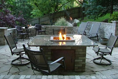 This is an example of a medium sized back patio in Grand Rapids with a fire feature, brick paving and no cover.