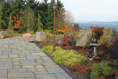 Large traditional back patio in Portland with natural stone paving.