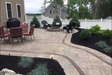 Example of a large classic backyard stone patio design in Boston with a fire pit and no cover