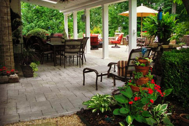 Example of a mid-sized mountain style backyard concrete paver patio design in Other with a fire pit and a roof extension