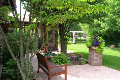 Modelo de patio tradicional de tamaño medio sin cubierta en patio trasero con adoquines de ladrillo y jardín de macetas