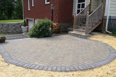 Example of a mid-sized classic backyard stone patio design in New York with no cover