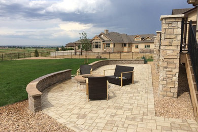 Example of a huge classic backyard stone patio design in Denver with a fire pit and no cover