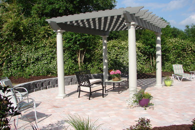Ejemplo de patio clásico grande en patio trasero con adoquines de hormigón y pérgola