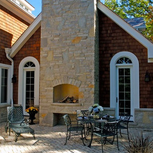 Idee per un ampio patio o portico classico dietro casa con pavimentazioni in mattoni, un focolare e nessuna copertura