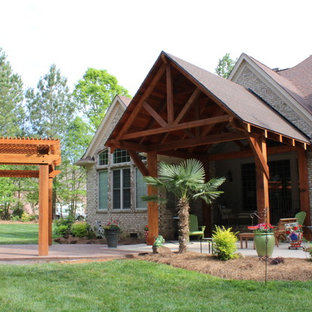 Esempio di un grande patio o portico american style dietro casa con un giardino in vaso, pavimentazioni in mattoni e un tetto a sbalzo