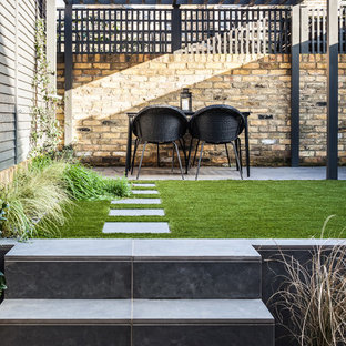 Design ideas for a medium sized contemporary back patio in London with natural stone paving and a pergola.