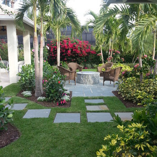 Inspiration for a tropical stone patio remodel in Miami with a fire pit