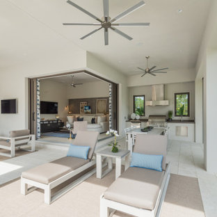 Large tuscan backyard concrete paver patio kitchen photo in Miami with a roof extension