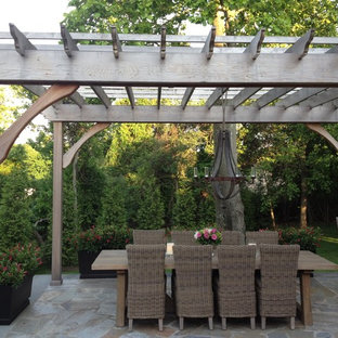 Idee per un patio o portico country dietro casa con pavimentazioni in pietra naturale e una pergola