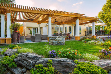 Patio - large traditional backyard stone patio idea in Other with a fire pit and a pergola
