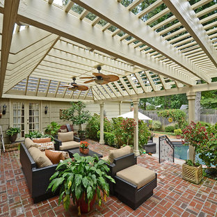 Idee per un grande patio o portico tradizionale dietro casa con una pergola, fontane e pavimentazioni in mattoni