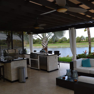 Ispirazione per un ampio patio o portico tropicale dietro casa con pavimentazioni in pietra naturale e una pergola