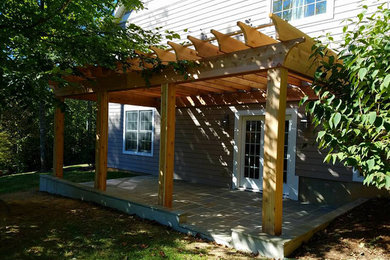 Mid-sized transitional backyard stone patio photo in Other with a pergola