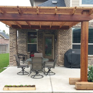 Ispirazione per un patio o portico american style di medie dimensioni e dietro casa con lastre di cemento e una pergola