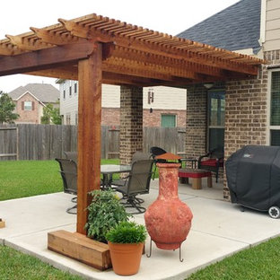 Immagine di un piccolo patio o portico american style dietro casa con lastre di cemento e una pergola