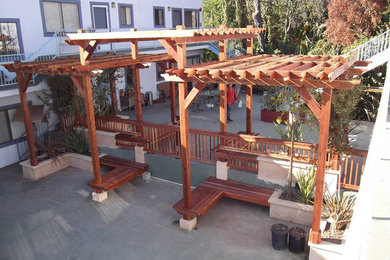 Example of a large backyard concrete paver patio design in Los Angeles with a pergola