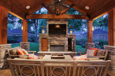 Example of a large mountain style backyard concrete patio design in Houston with a fire pit and a roof extension