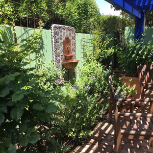 Immagine di un piccolo patio o portico eclettico dietro casa con fontane, pavimentazioni in mattoni e una pergola
