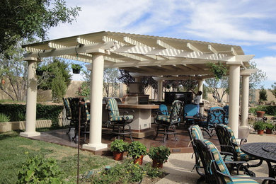 Patio kitchen - mid-sized southwestern backyard stone patio kitchen idea in Phoenix with a pergola