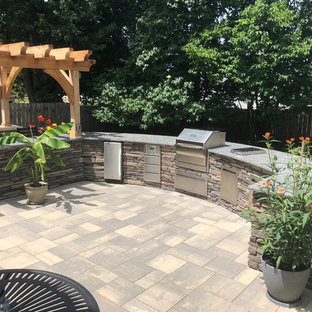 Foto di un ampio patio o portico eclettico dietro casa con pavimentazioni in mattoni e una pergola