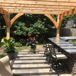 Idee per un ampio patio o portico eclettico dietro casa con pavimentazioni in mattoni e una pergola