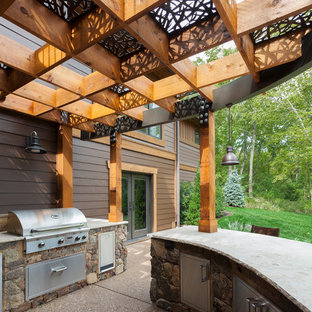 Immagine di un grande patio o portico american style dietro casa con lastre di cemento e una pergola