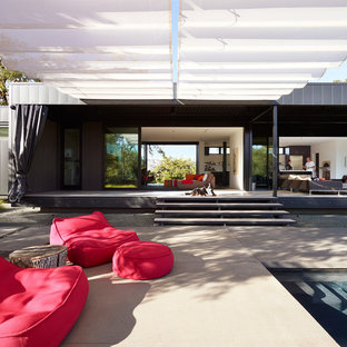 Foto di un patio o portico minimalista dietro casa con lastre di cemento e un parasole