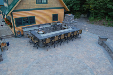 Modelo de patio rústico extra grande en patio lateral con cocina exterior y adoquines de hormigón