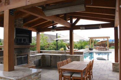 Foto de patio clásico en patio trasero con cocina exterior, adoquines de piedra natural y pérgola