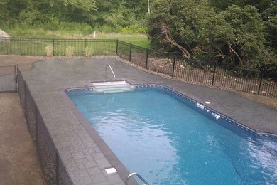 This is an example of a back swimming pool in Boston with concrete paving.