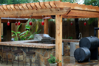 ヒューストンにある中くらいなトラディショナルスタイルのおしゃれな裏庭のテラス (アウトドアキッチン、天然石敷き、パーゴラ) の写真