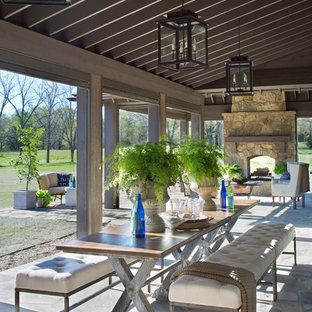 Idee per un patio o portico country dietro casa con un focolare, pavimentazioni in pietra naturale e un tetto a sbalzo